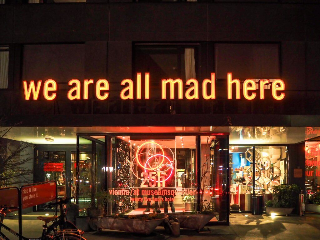 Exterior of 25 hours hotel in Vienna with neon sign that reads "we are all mad here".