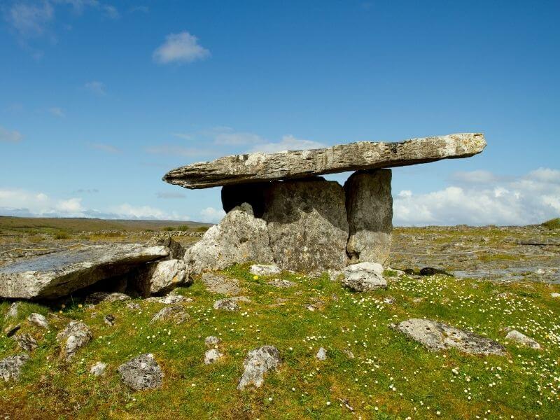 A large flat stone being held up by four vertical stones. A traditional burial site of Polnabrone Dolmen in The Burren in County Clare Ireland