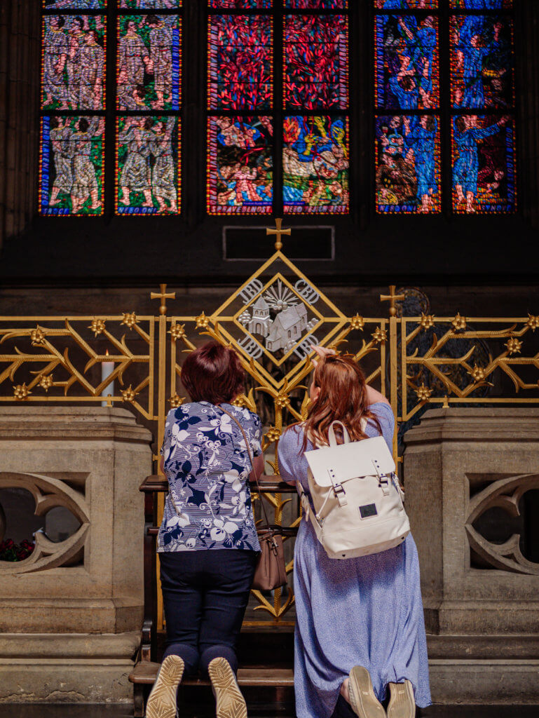 Woman praying with her daughter in law at St Vitus Cathedral in Prague