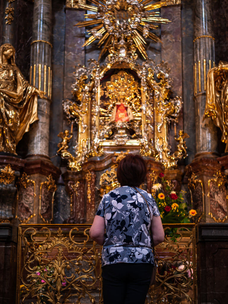 Woman in the church of our lady of victories looking up at the infant child of Prague during a two day trip to Prague