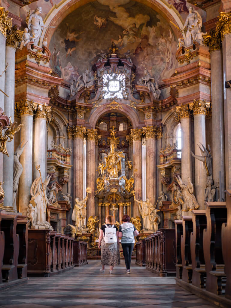 Two women walking inside St Nicholas Church in Prague