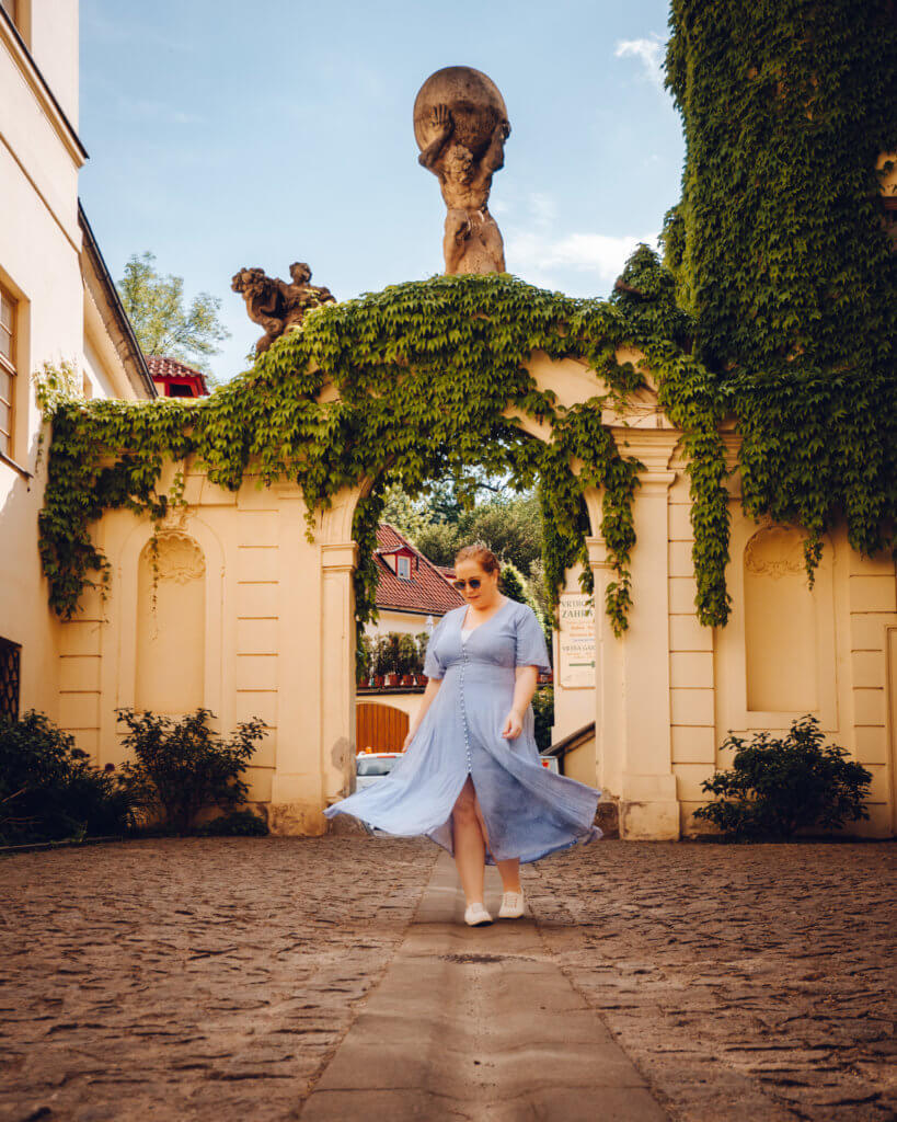 Woman wearling a blue dress twirling in Vrtbovska gardens in Prague on a 2 day trip to Prague