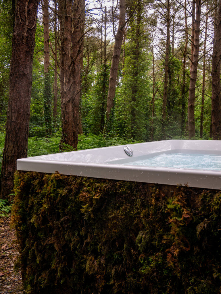 Outdoor whirlpool bath covered in moss at Burrenmore Nest.