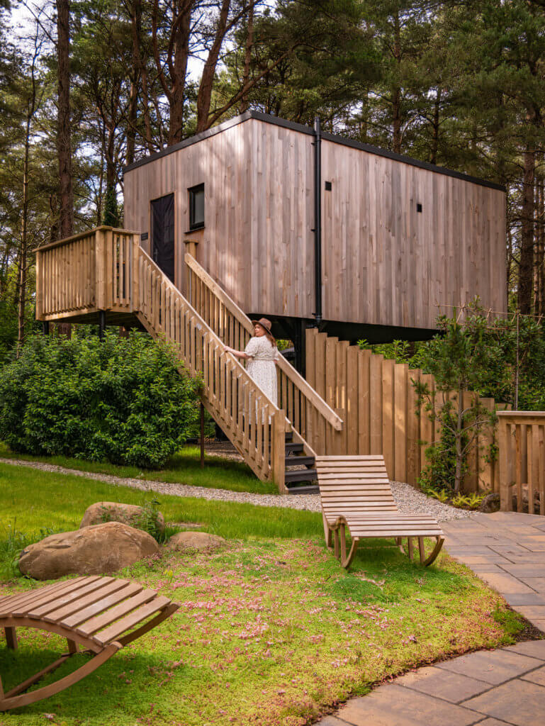 Woman walking up wooden steps to reach a romantic treehouse Ireland