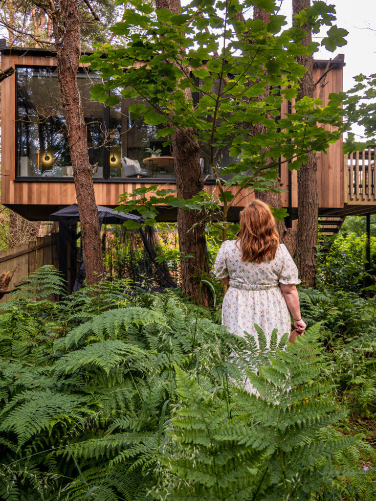 Woman in a floral dress looking at her luxury treehouse Ireland