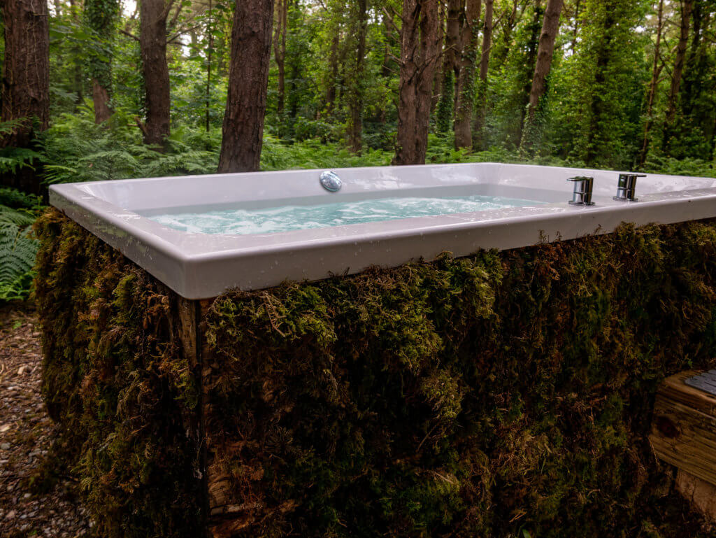 Moss covered outdoor whirpool bath in the forest at Burrenmore Nest Ireland