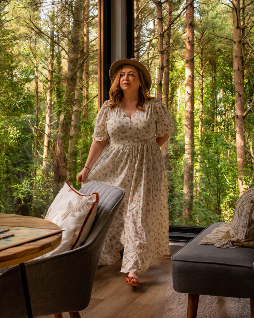 Woman in a floral dress and a brown hat in a luxury treehouse in Ireland