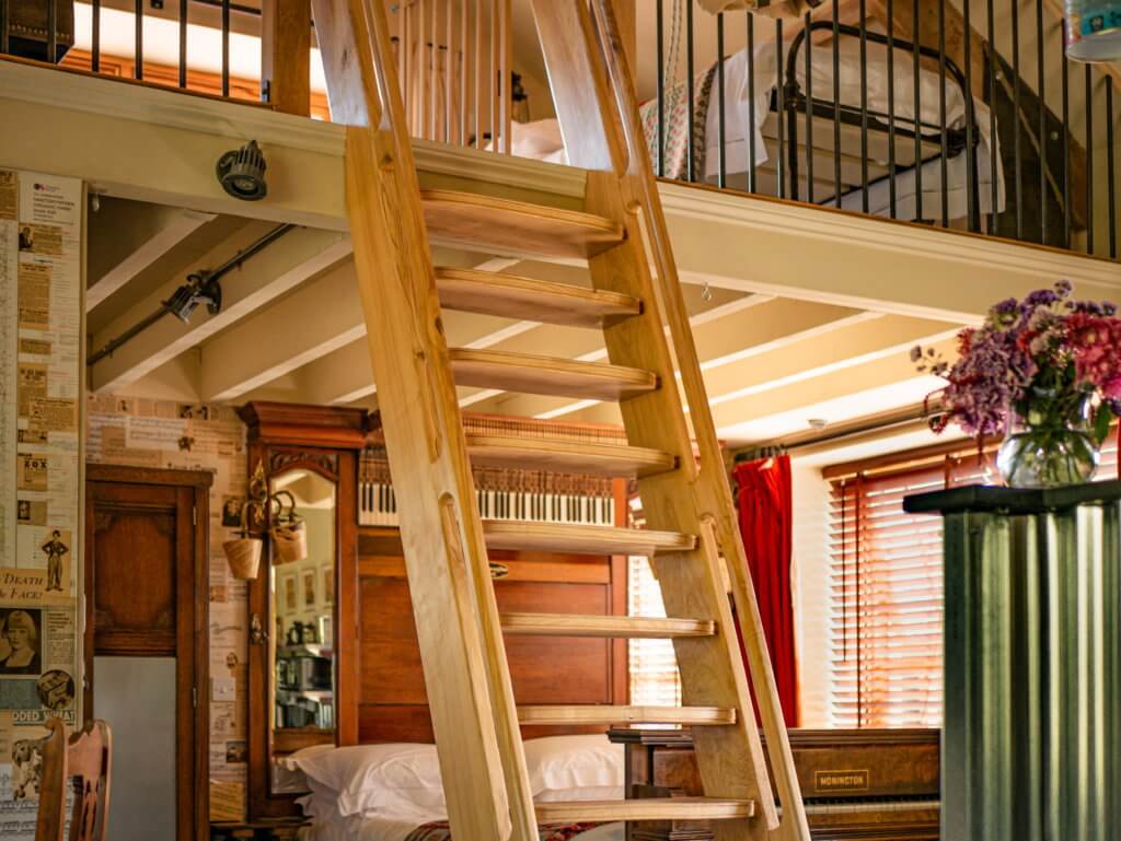 A ship's ladder going up to a mezzanine single bedstead at accommodation in an organic farm in Wales