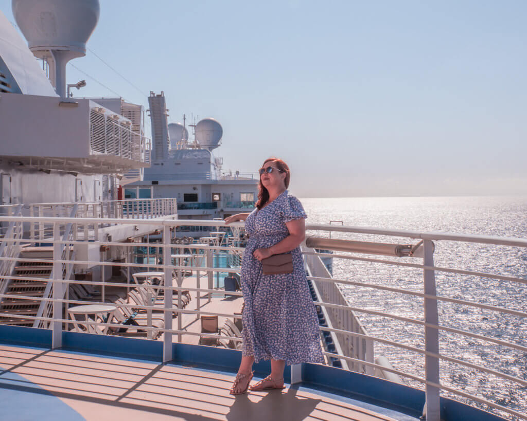 Woman in a blue dress standing on the deck of Sky Princess on her first cruise on Princess Cruises
