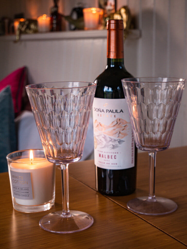 A bottle of red wine with two glasses and scented candles.