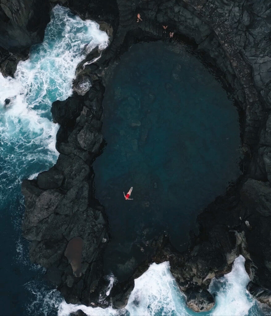 Aerial view of a woman in a red swimming suit swimming in charco de la laja natural swimming pool in Tenerife