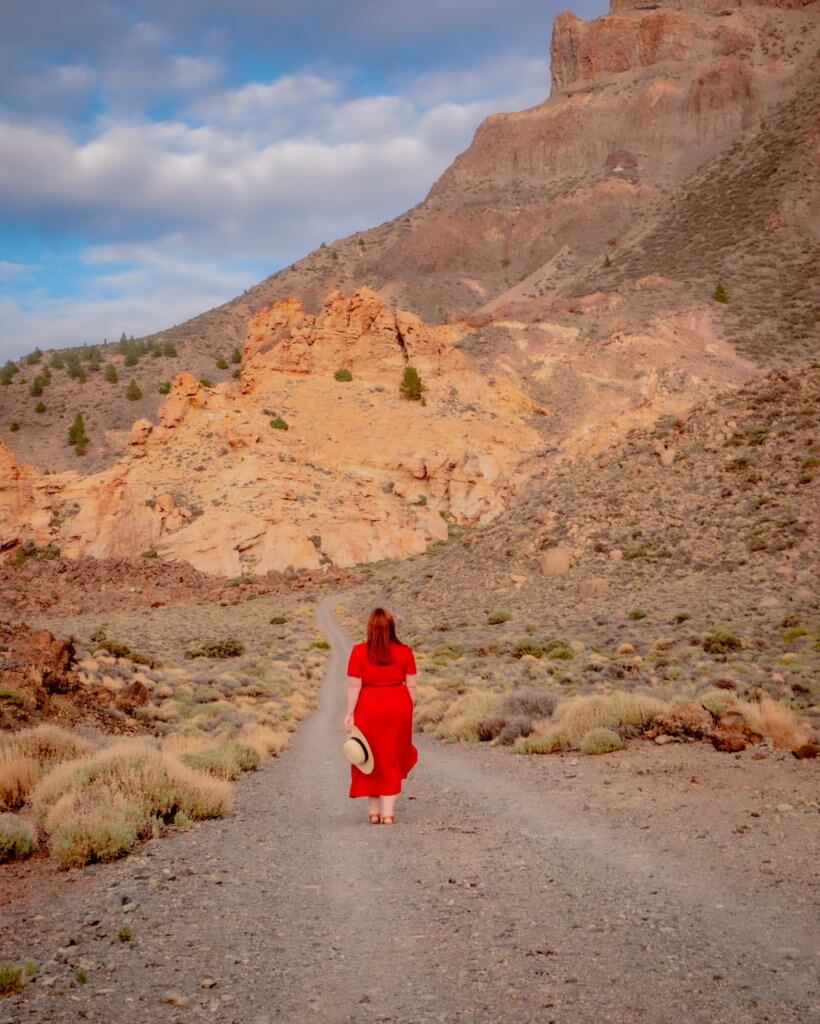 Woman in a red dress walking in the lunar landscape of Mount Teide National Park Tenerife