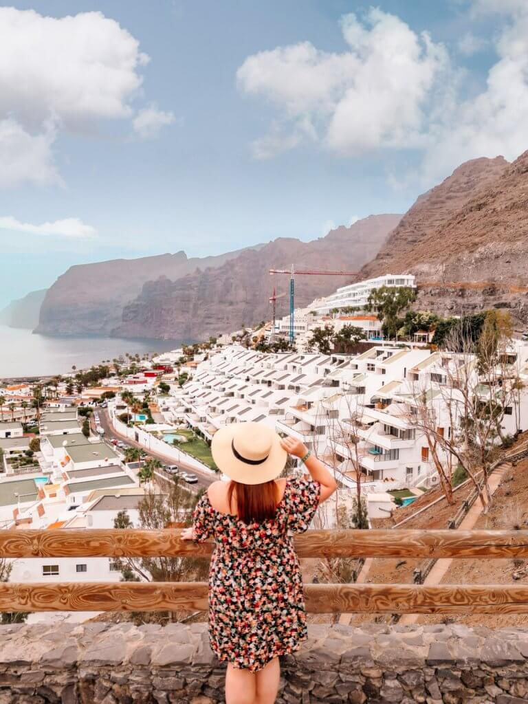 Woman in a floral dress and a straw hat overlooking Los Gigantes Cliffs in Tenerife