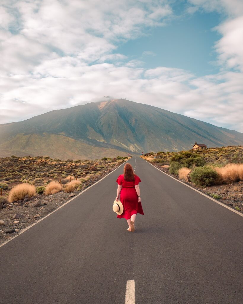 Woman walking on a long road towards Mount Teide Volcano in Tenerife
