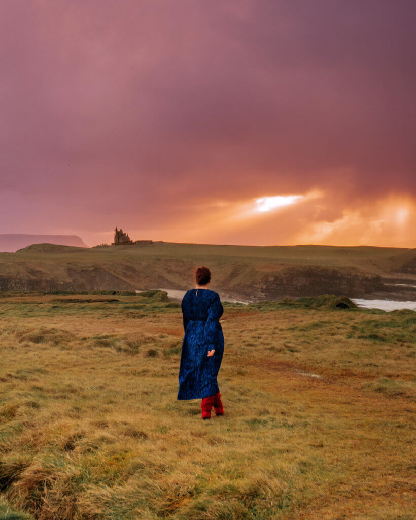Woman in a blue dress looking at Classiebawn Castle in Sligo Ireland at sunset.