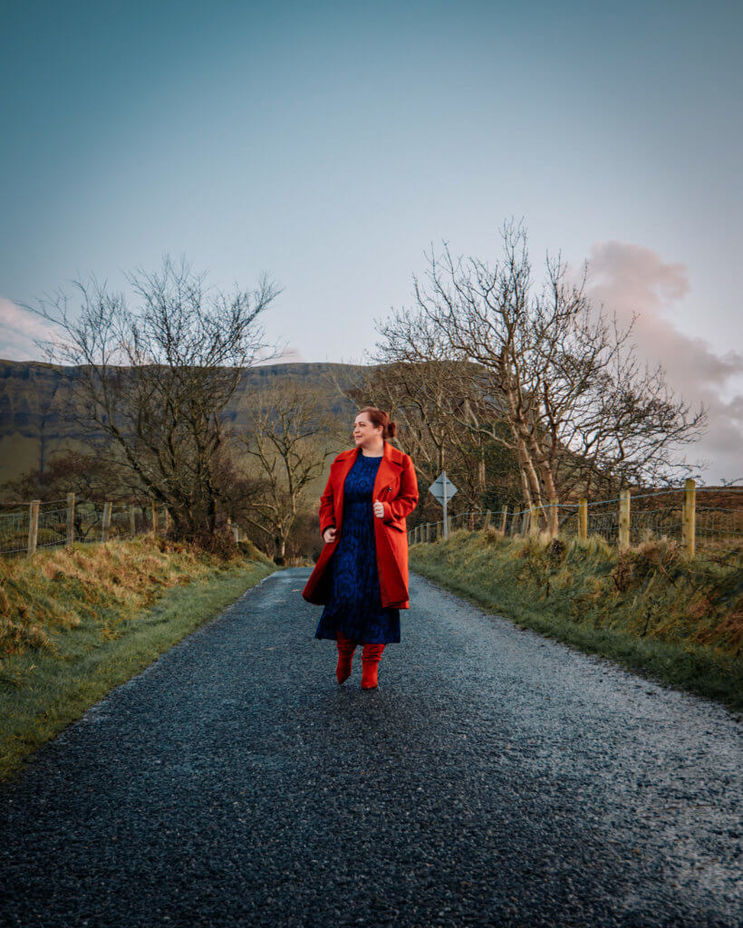 Woman in a red coat walking on a road near Benbulben in Sligo Ireland