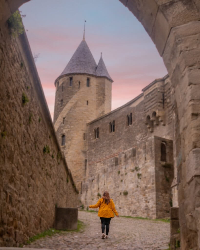 Woman in a yellow rain jacket walking along the ramparts of Cite de Carcassonne