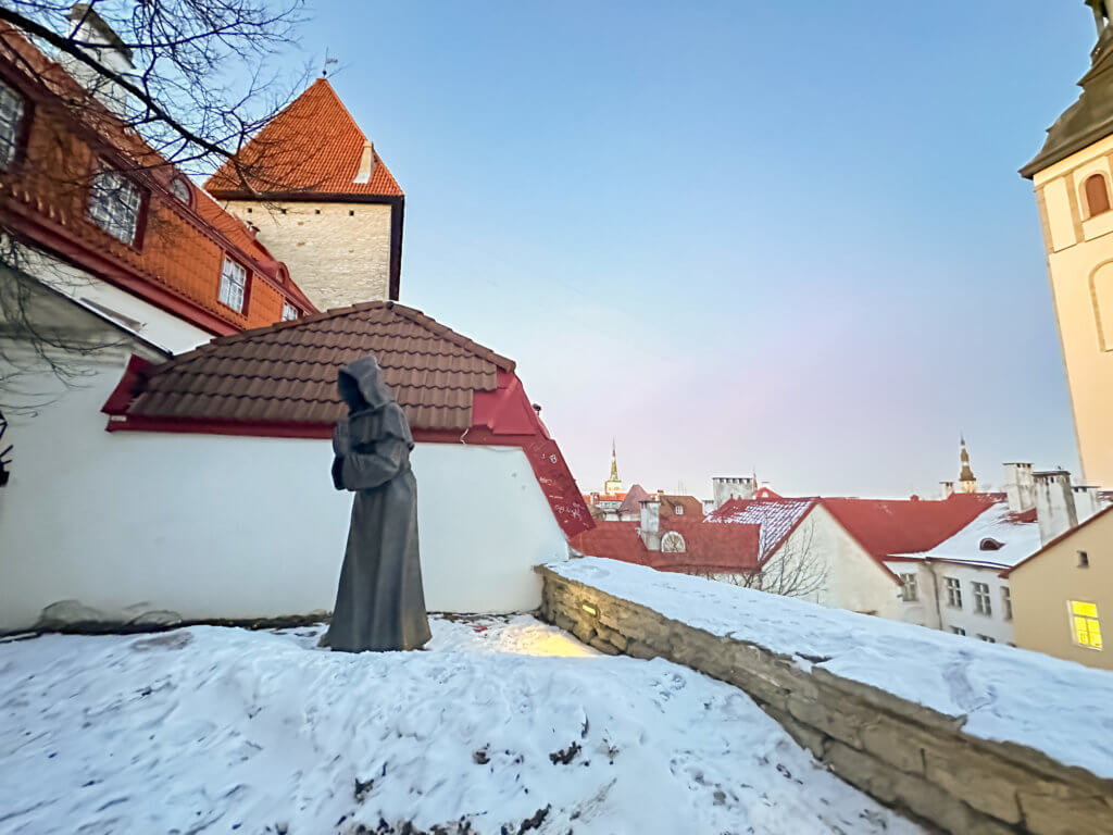 Praying monk statue in the snow in the Danish Kings Garden in Tallinn Estonia in winter