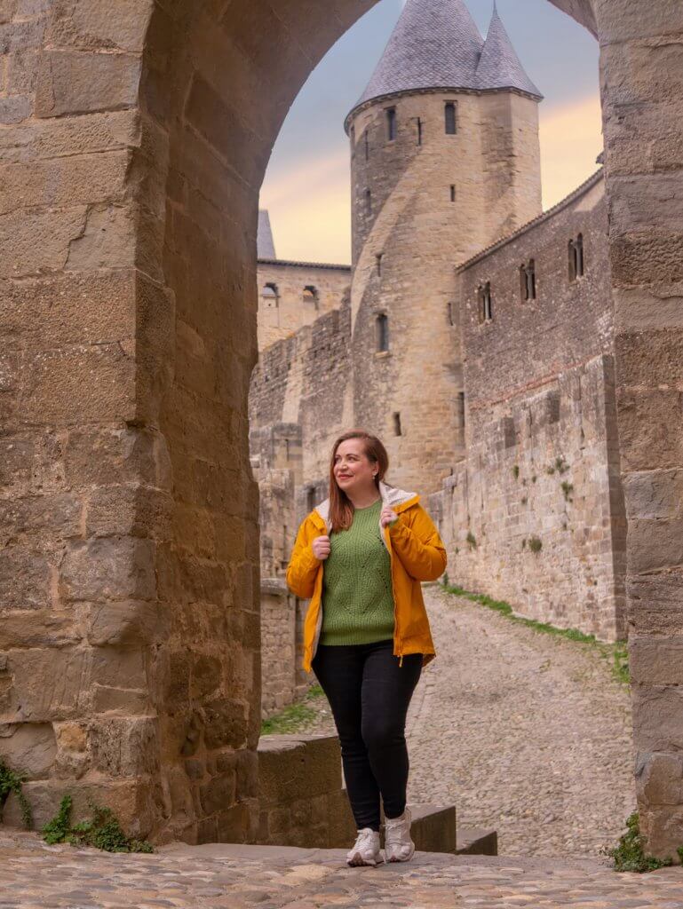 Woman in a yellow rain coat walking around the city walls of Carcassonne France