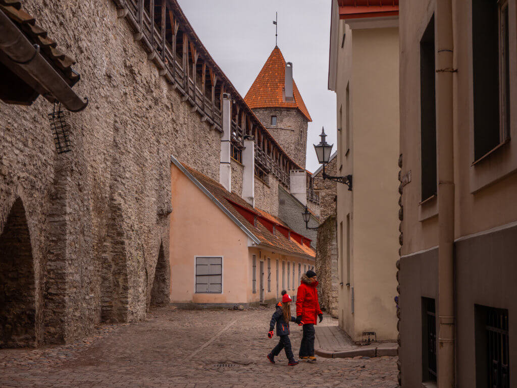 People walking along Tallinn's medevial streets wearing winter clothes