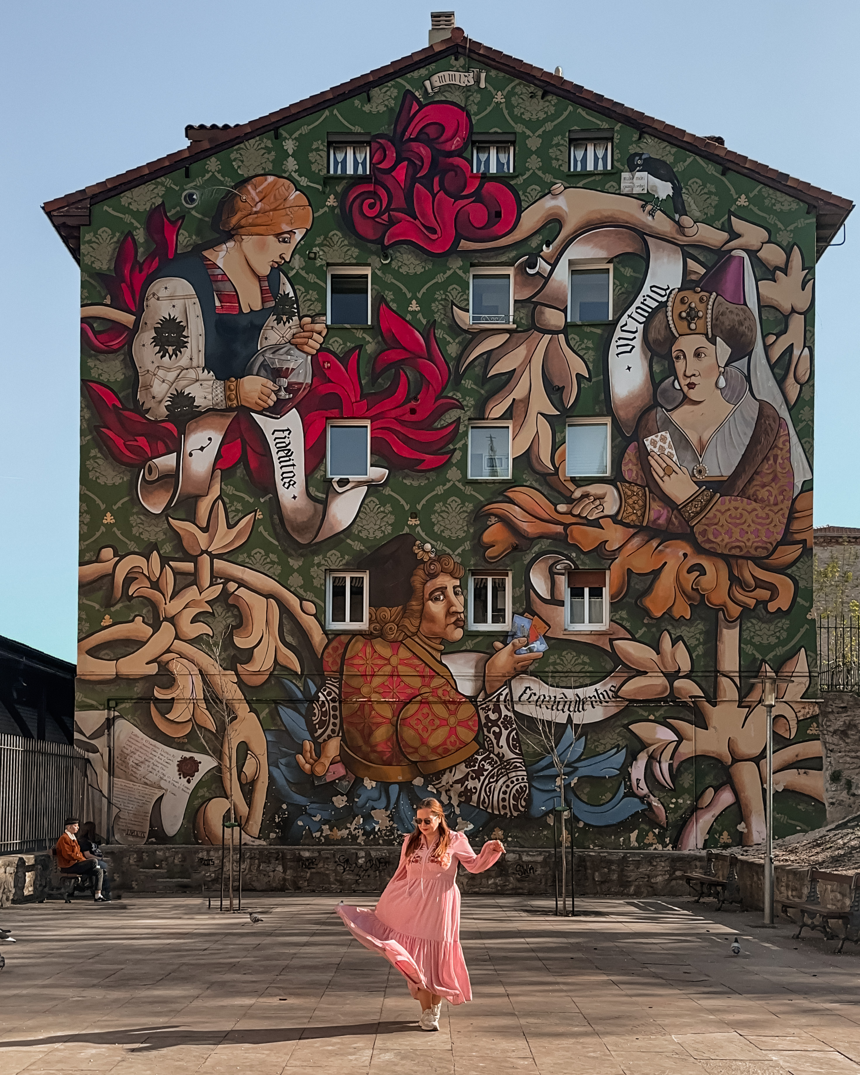 Woman in a pink dress having her photo taken in front of a mural in Vitoria Gasteiz