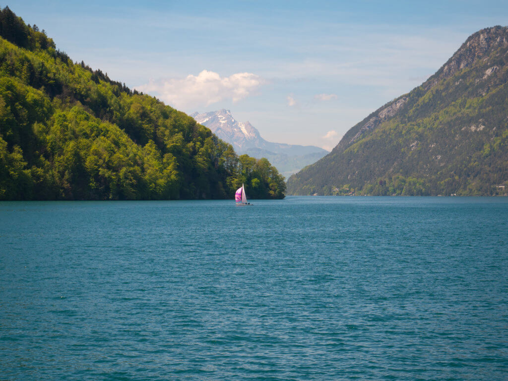 Pink sailboat on Lake Lucerne surrounded by mountains