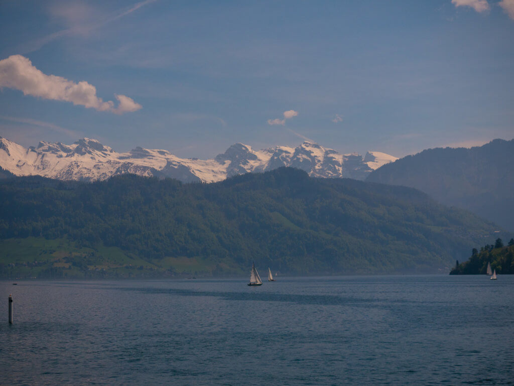 Sailboats on Lake Lucerne surrounded by snow capped mountains