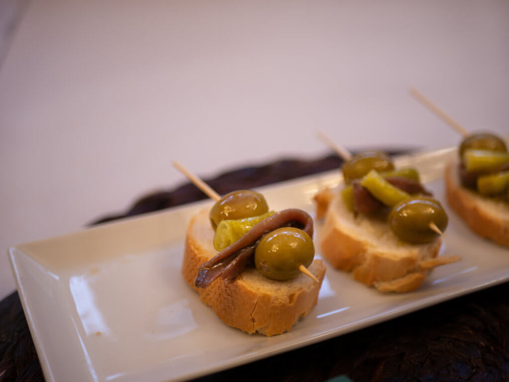 A plate of gilda pintxos with anchiovy, olives and peppers on bread