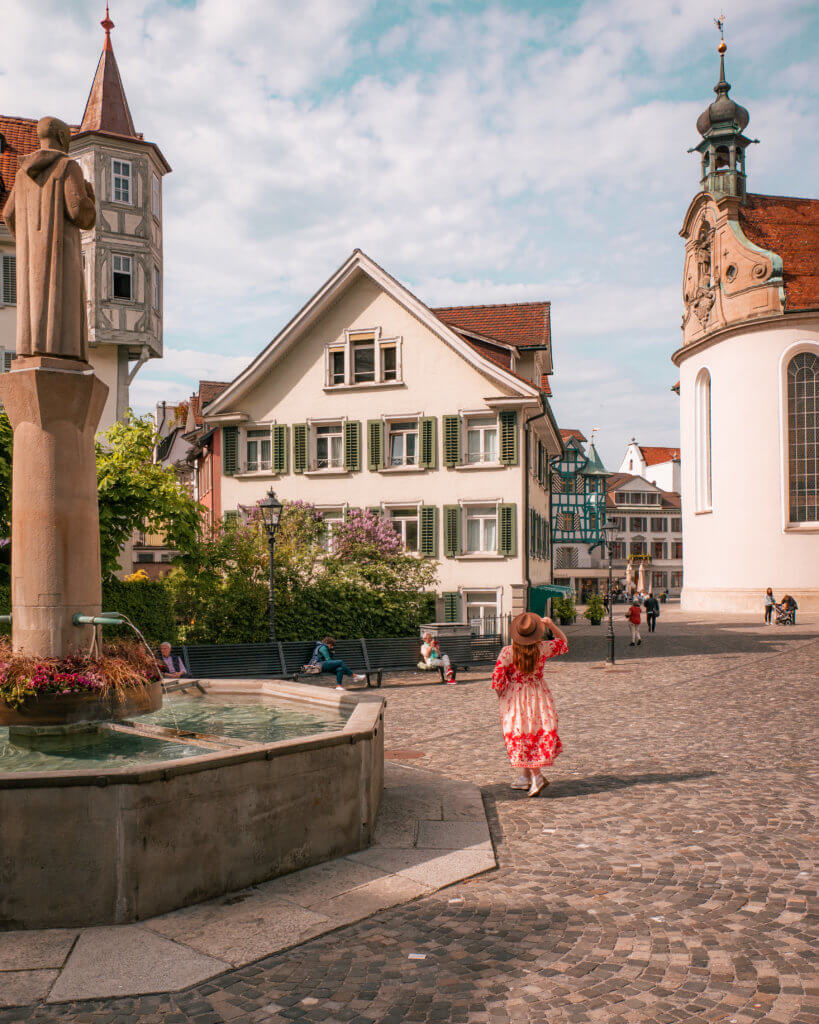 Nicola wearing a floral dress and a fedora hat exploring the fairytale Swiss city of St. Gallen Old Town