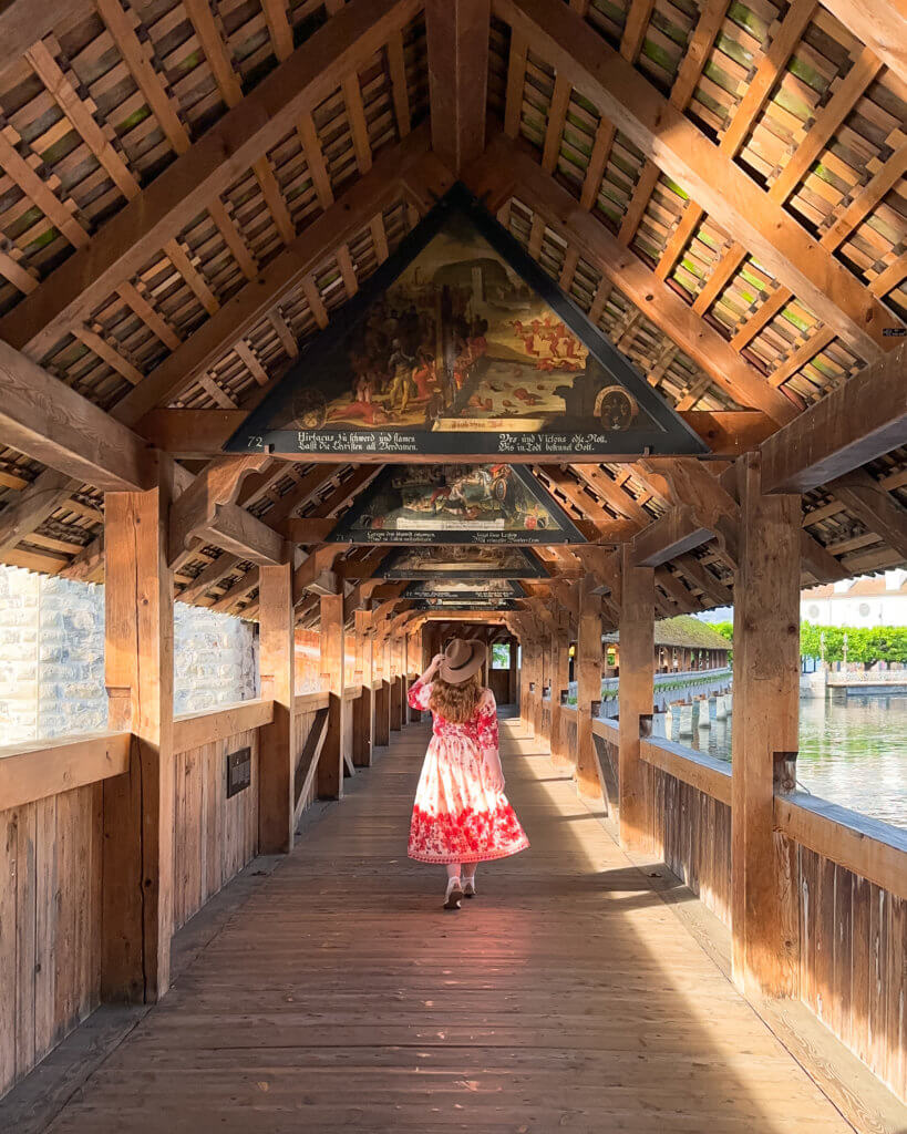 Nicola Lavin Travel Blogger walks on the famous wooden Chapel Bridge in Lucerne Switzerland during one day in Lucerne.