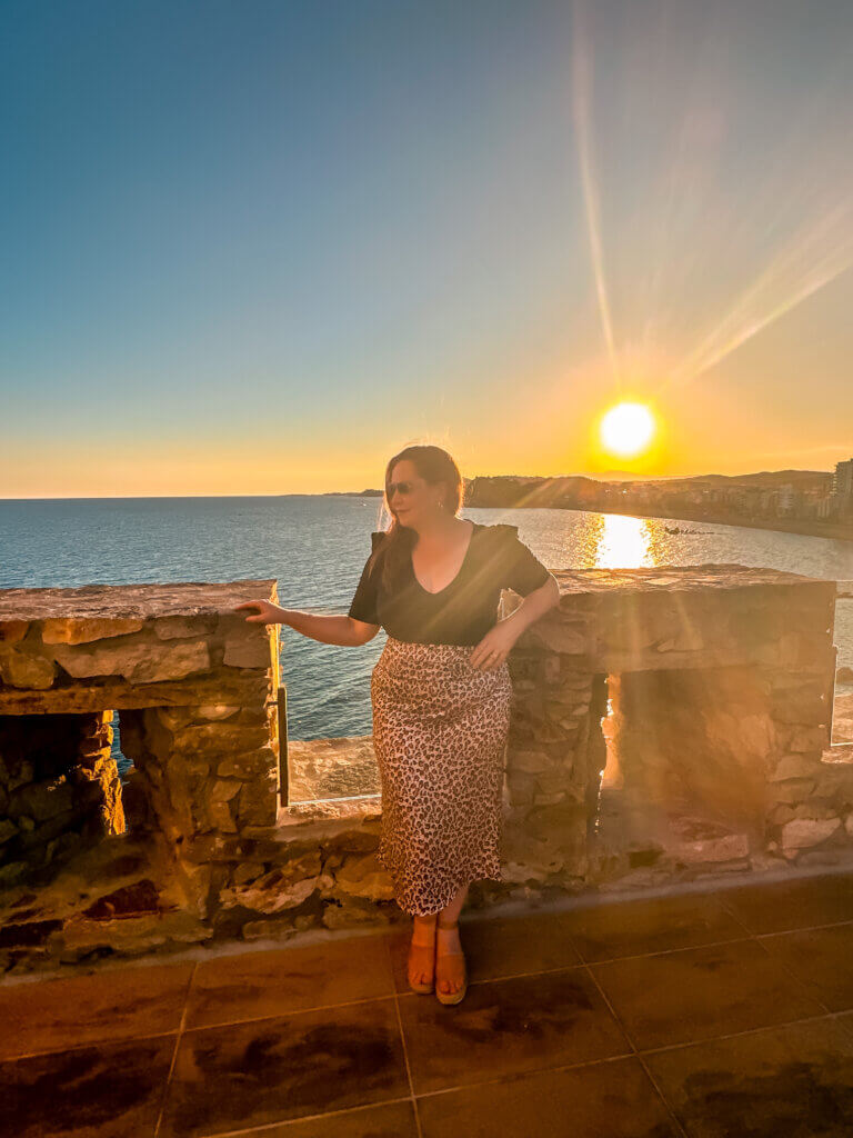 Nicola Lavin, Irish travel blogger stands at Lloret Castle at sunset