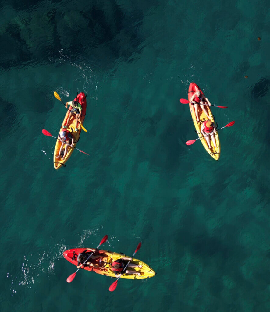 Three yellow and red kayaks in blue water