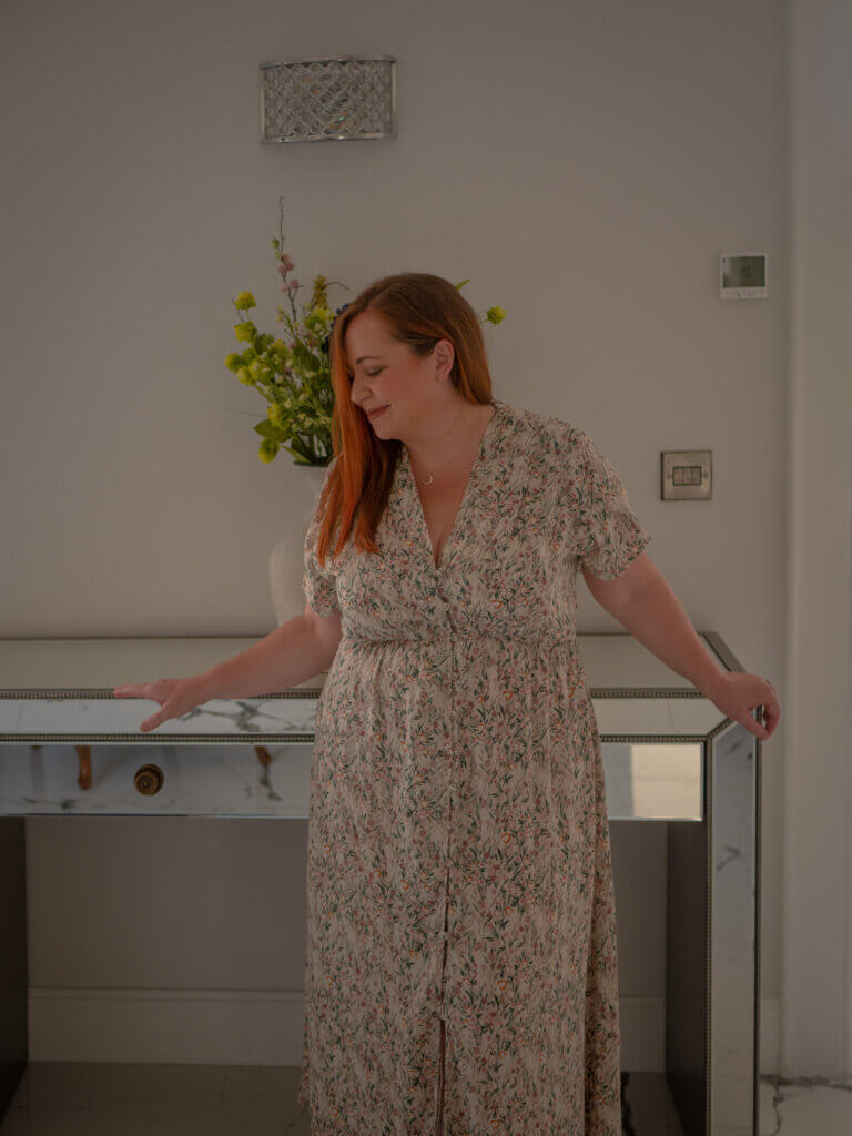 Woman with red hair wearing a long floral dress.