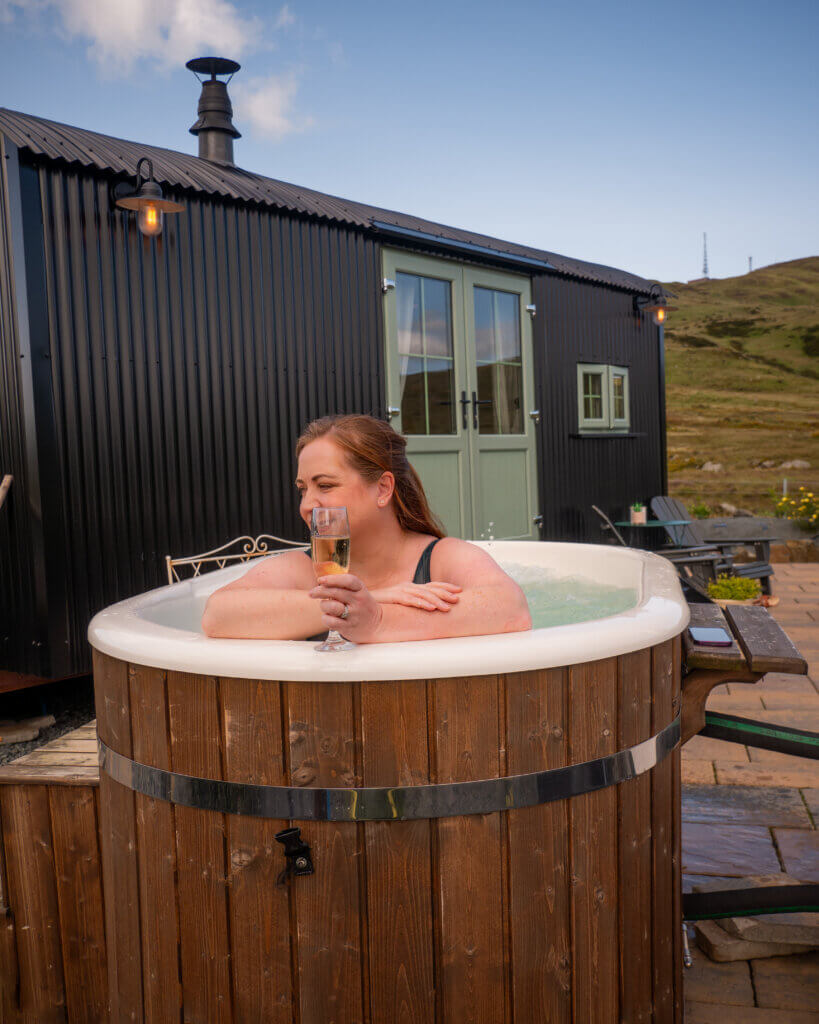 Woman drinking champagne in a hot tub at a unique airbnb in Northern Ireland.
