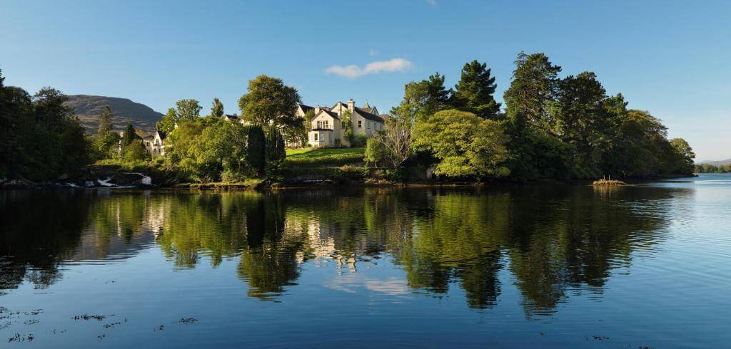 Sheen Falls Lodge exterior, showcasing its elegant architecture amidst lush greenery in Kenmare, Ireland.