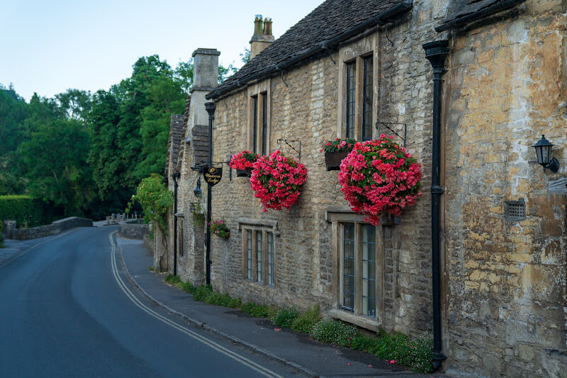Quaint country pub framed by colourful flowers in the Cotswolds.