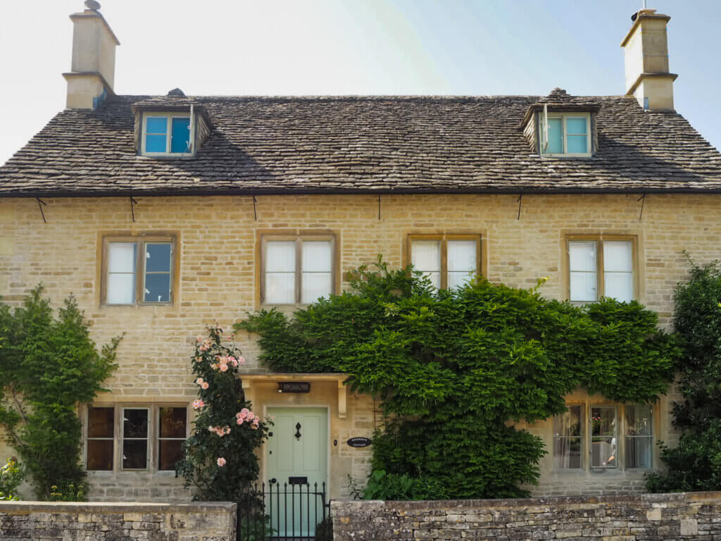 Honey-coloured stone cottage surrounded by colourful gardens in the Cotswolds.