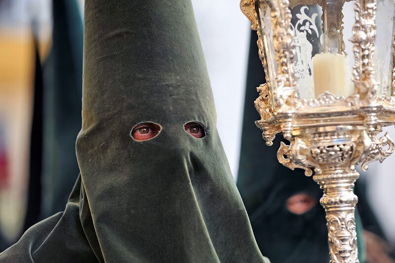 Dramatic Semana Santa procession in Toledo, with hooded figures carrying statues of religious significance.