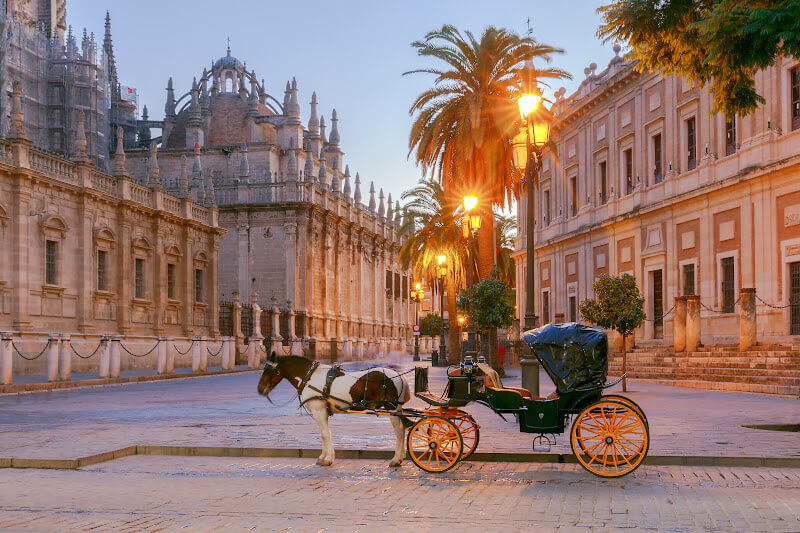 Horse and carriage waiting for tourists at Seville city centre. There is a backdrop of beautiful architecture in this historic city.