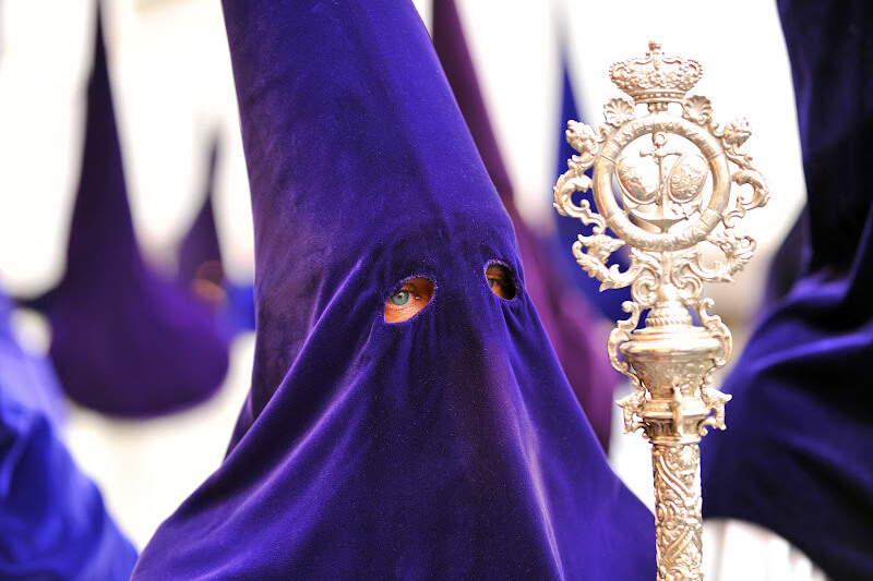 Mesmerizing Easter parade in Seville: a procession of hooded figures carrying ornate floats.