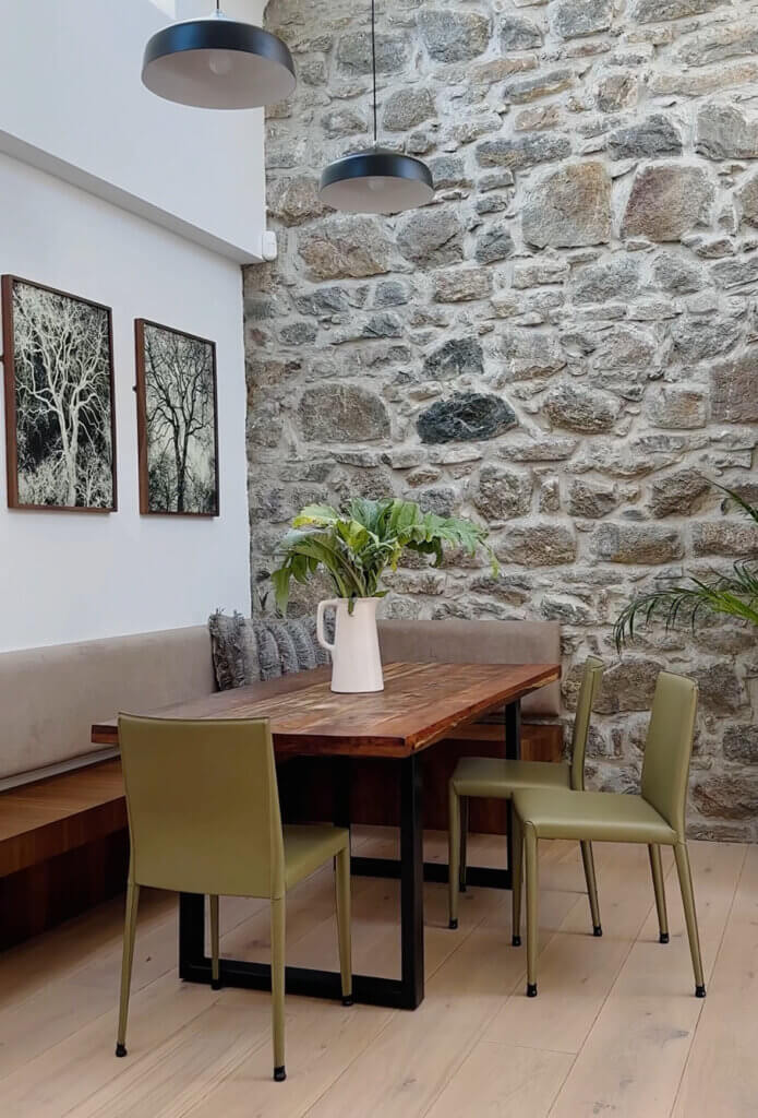 Dining table against a reclaimed stone wall in Within the Village in Roundstone, Connemara.