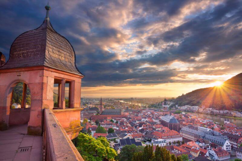 Sunset over Heidelberg, casting a warm glow on the Neckar River and surrounding hills.