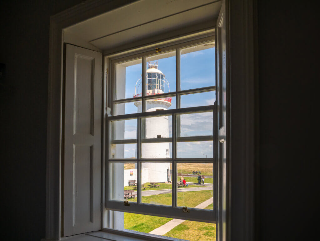 The view from the window inside the cottage, overlooking the lighthouse and the sea.