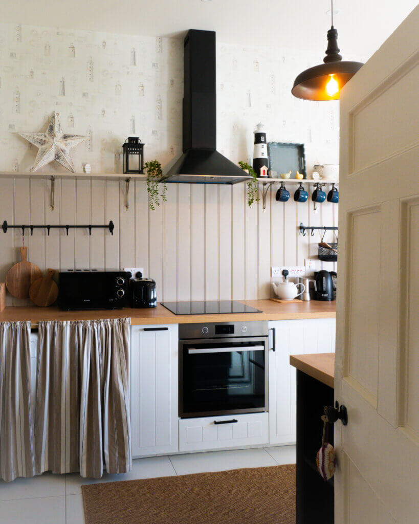 The kitchen in Loop Head Lighthouse cottage, fully equipped with rustic wooden cabinets.