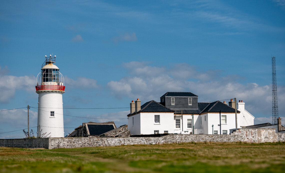 Loop Head Lighthouse on a bright sunny day, standing tall against a clear blue sky.