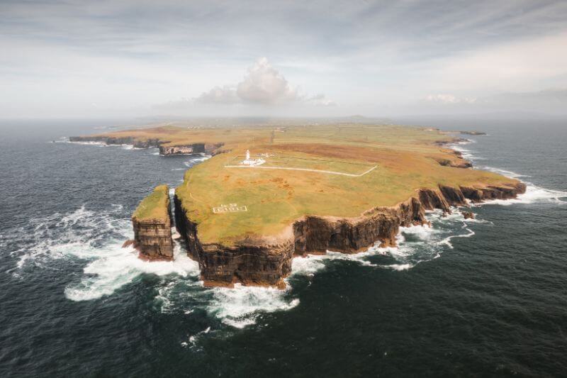 Aerial shot of Loop Head Lighthouse perched on the rugged Irish coastline.