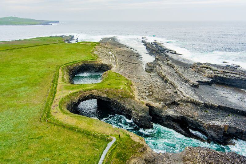 Waves crashing against the rocks at the Bridge of Ross on the Wild Atlantic Way in Ireland.